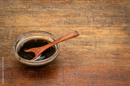 a small bowl of yacon syrup against rustic weathered wood,  a powerful prebiotic sweetener derived from the yacon root