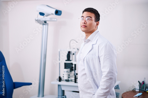 Pensive male ophthalmologist in eyeglasses looking away