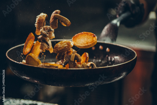 Chef at work. Hand holds a hot pan with fried vegetables  photo