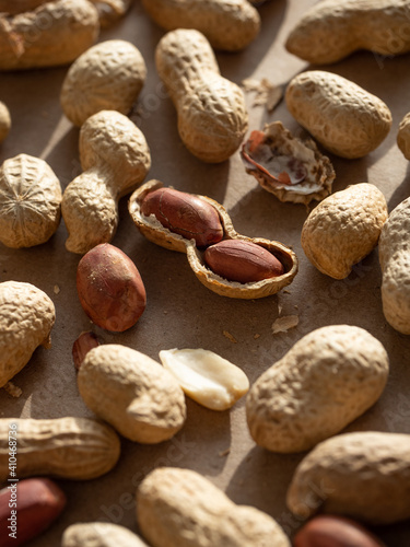 Peanuts in shells and peeled scattered on brown craft paper in the morning light