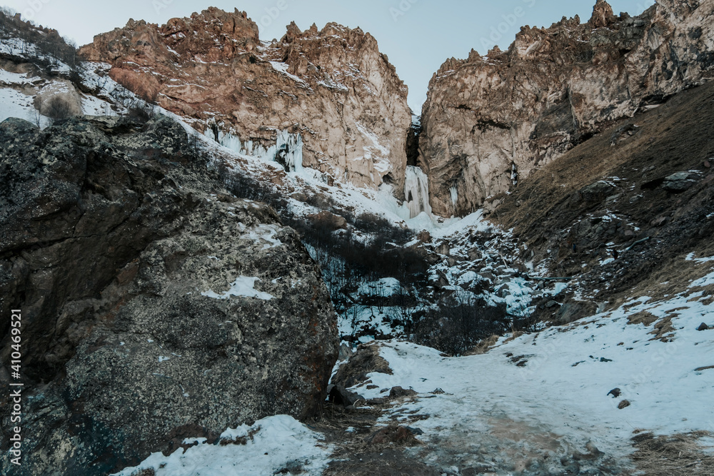 Photo of a frozen waterfall in the mountains in winter. Mountains of Russia, North Caucasus. Photo of a frozen waterfall in the mountains in winter. Mountains of Russia, North Caucasus.