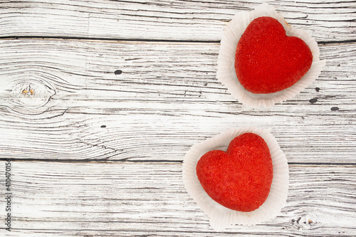 A bright red heart-shaped cakes on a wooden background. Copy space