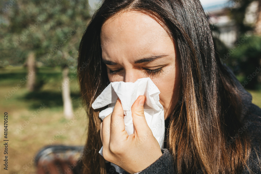 The woman blows her nose into a handkerchief. A symptom of an illness or allergy The woman blows her nose into a handkerchief. A symptom of an illness or allergy