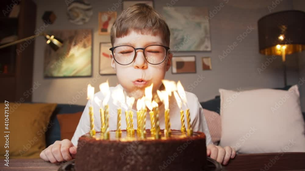 Children kid boy blow out candles on birthday cake, celebrating birthday together at home, video camera view of blowing candle and making wish