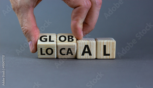 Local or global symbol. Hand turns cubes and changes the word 'local' to 'global'. Beautiful grey background. Business and local or global concept. Copy space.