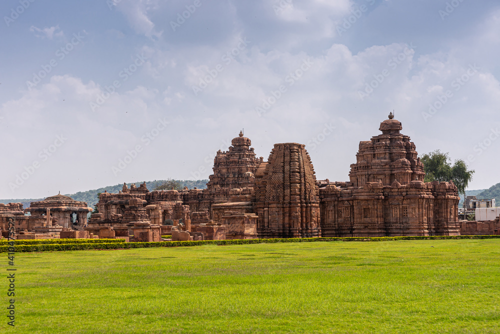 Bagalakote, Karnataka, India - November 7, 2013: Pattadakal temple complex. Brown stone combination of Galaganatha and Sangameshwara temple under blue cloudscape. Security guard.