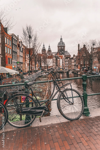 Bicycle parked on a bridge. Cloudy day in Amsterdam. Picturesque town landscape