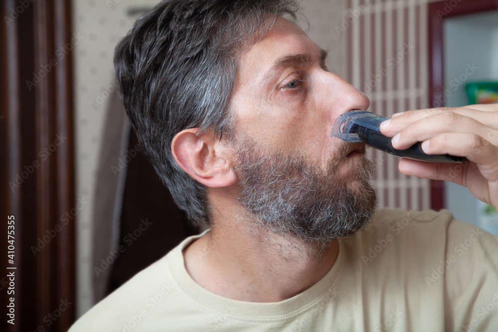 Obraz premium Haircut beard with gray hair trimmer close-up