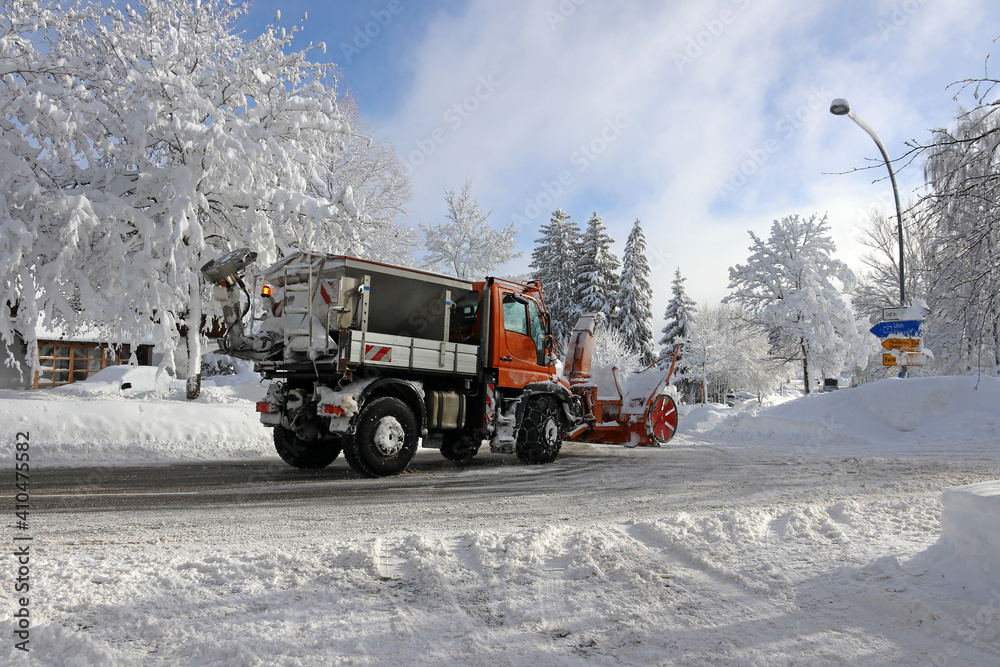 Ein Schneepflug mit einer Schneefräse fährt im Winter in einer Stadt durch die Straße um den hohen Schnee wegzuräumen Ein Schneepflug mit einer Schneefräse fährt im Winter in einer Stadt durch die Straße um den hohen Schnee wegzuräumen