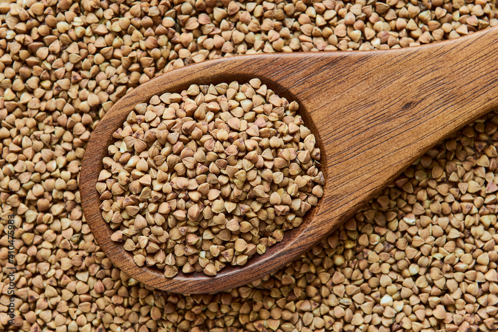 Uncooked dried buckwheat in a wooden spoon, close up, macro Uncooked dried buckwheat in a wooden spoon, close up, macro
