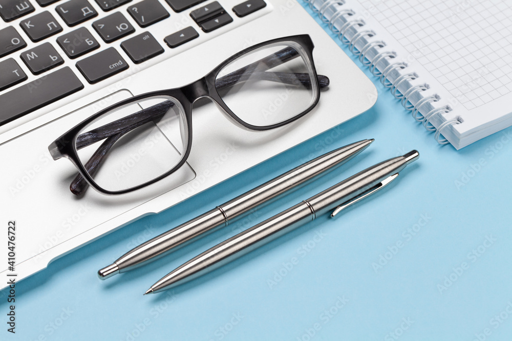 Office desk with supplies, glasses and laptop