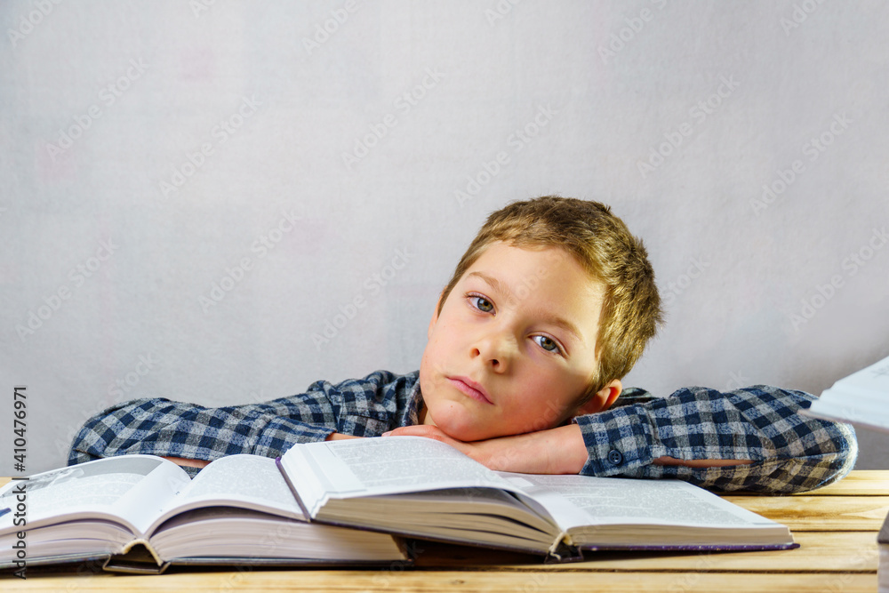 Tired, sad boy among open books.