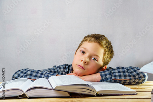 Tired  sad boy among open books.