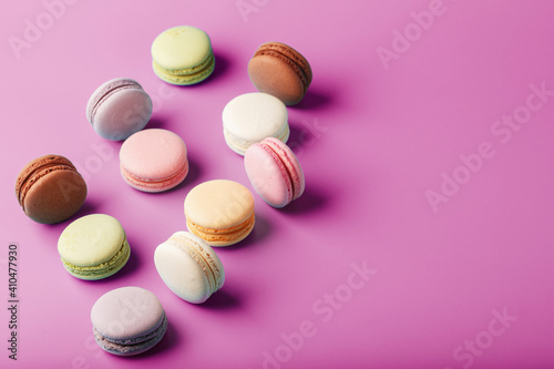 Colorful French macaroni cookies are scattered on a pink background.