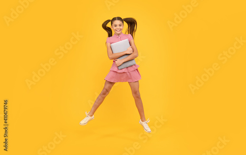 cheerful teen girl jump hold computer for study online, school