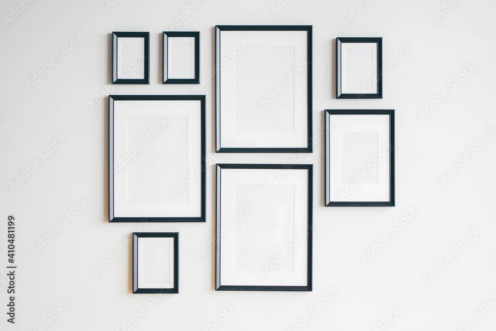 Multiple many black picture frames on white wall. Woman hanging a frame on  a wall. Stock Photo | Adobe Stock
