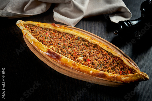 Turkish pide with minced lamb, tomatoes, bell pepper on a black background