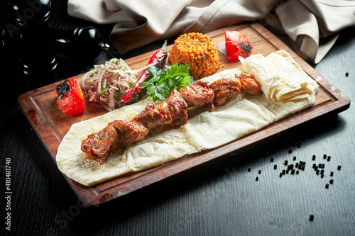 Chicken kebab cooked on the grill with lavash, bulgur and grilled vegetables on a wooden board. Turkish kebab. Close up ,selective focus