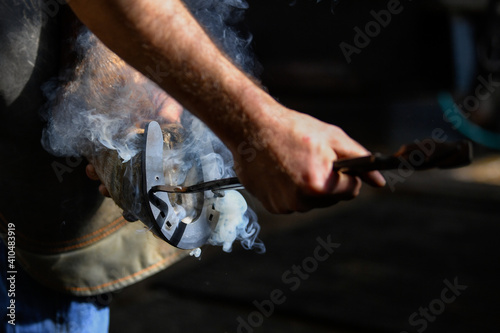 Farrier hot shoeing a horse - adjusting a hot horseshoe to the hoof