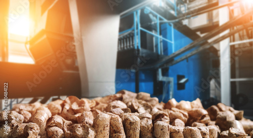 Wood pellets for heating industrial boiler houses with bio fuel. Composite mixed media image of woody biomass close-up against the background of industrial boilers. Modern energy concept