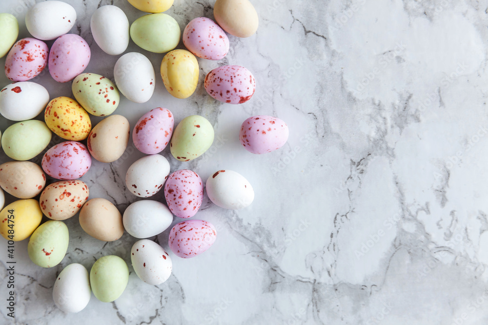 Happy Easter concept. Preparation for holiday. Easter pastel candy chocolate eggs sweets on trendy gray marble background. Simple minimalism flat lay top view copy space.