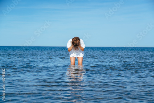 Curly girl standing in ocean