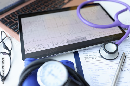 Digital tablet with electrocardiogram lying on doctors desk closeup photo
