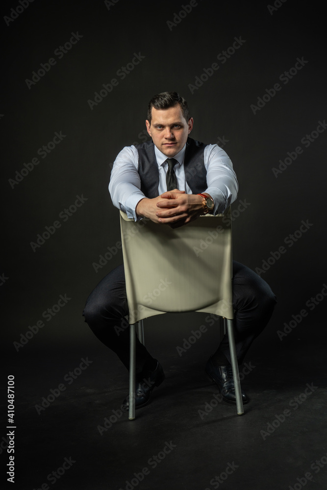 in a three-piece suit on a chair Young man three piece suit business caucasian fashion, young guy clothes. Elegant shirt lonely background black bodybuilder in a three-piece suit on a chair Young man three piece suit business caucasian fashion, young guy clothes. Elegant shirt lonely background black bodybuilder