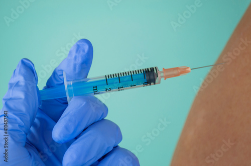 a doctor in medical gloves puts a vaccine against the coronavirus flu with a syringe to a patient