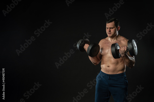 Man strains muscles with dumbbells pumps bicep bare torso Young male business Caucasian beautiful, happy. trendy, cool black bodybuilder background
