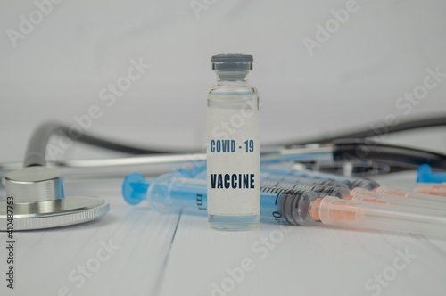 vaccine liquid drug for the prevention of coronavirus against the background of syringes and stethoscope