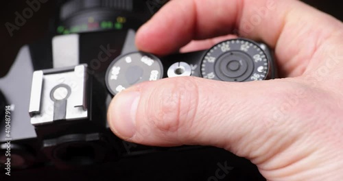 Old black analogue film camera in hands with adjusting parameters of iso aperture and timing