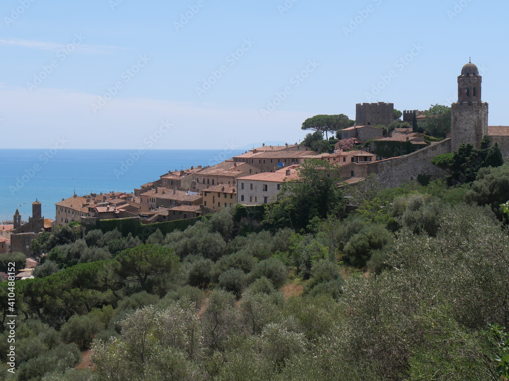 Panorama of the fortified medieval village of Castiglione della Pescaia perched on the top of a hill with the Tyrrhenian Sea in the background.