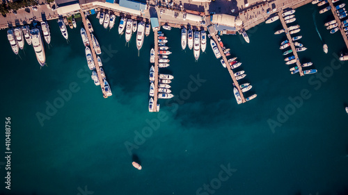 Aerial view of the bay with a lot of white boats and yachts at sunset on sunny day. View from above of pier for pleasure boat and sailboats in marina with beautiful turquoise sea.