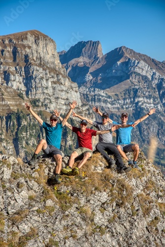 4 brothers hike in the swiss mountains and take a group picture infront of hike peak mountains of zuestoll churfirsten. photo