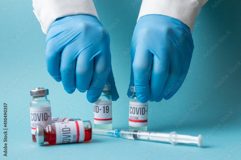 Covid-19 or coronavirus vaccine in doctor hands, nurse in blue gloves holding ampoule and syringe Covid-19 or coronavirus vaccine in doctor hands, nurse in blue gloves holding ampoule and syringe