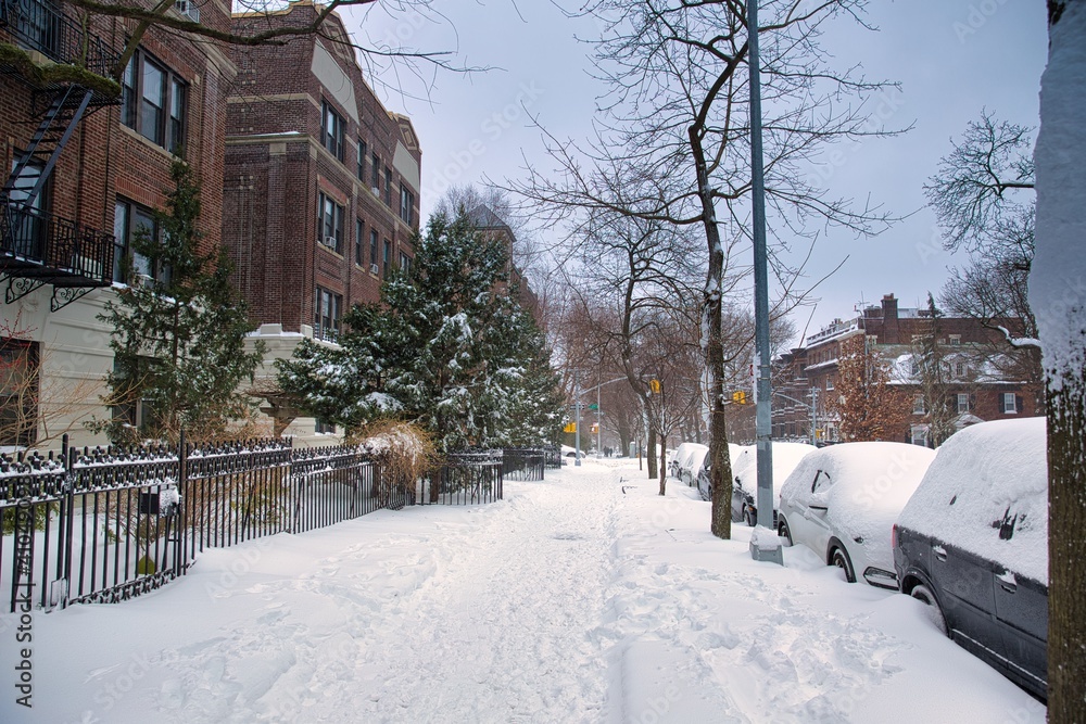 Winter scene with snow covered cars parked along streets in Brooklyn, NY. Brownstones in winter season
