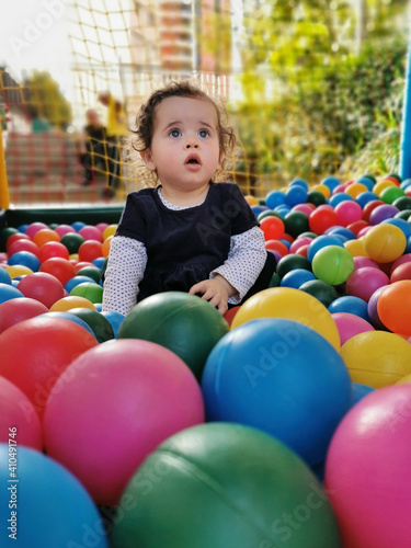 Little baby playing alone in the ball pit