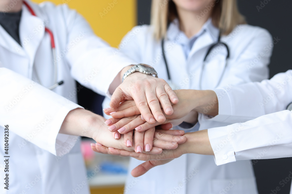 Group of doctors putting their hands together in clinic closeup Group of doctors putting their hands together in clinic closeup