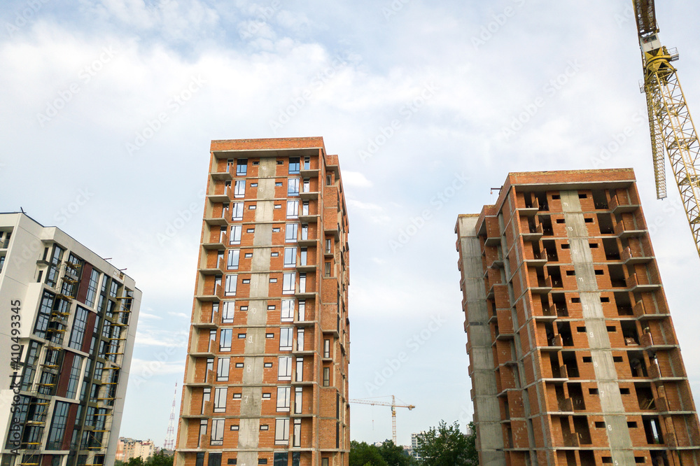 Fototapeta premium High-rise residential apartment buildings and tower crane under development on construction site. Real estate development.