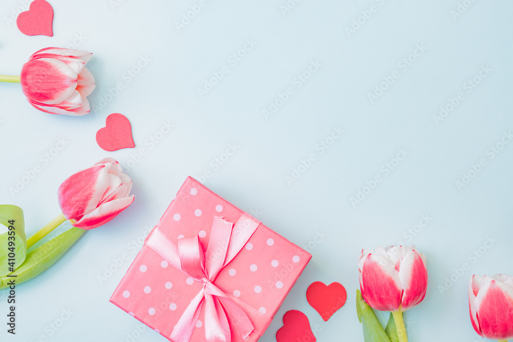 Flat lay valentines day frame with pink tulips and gift box on a light green background