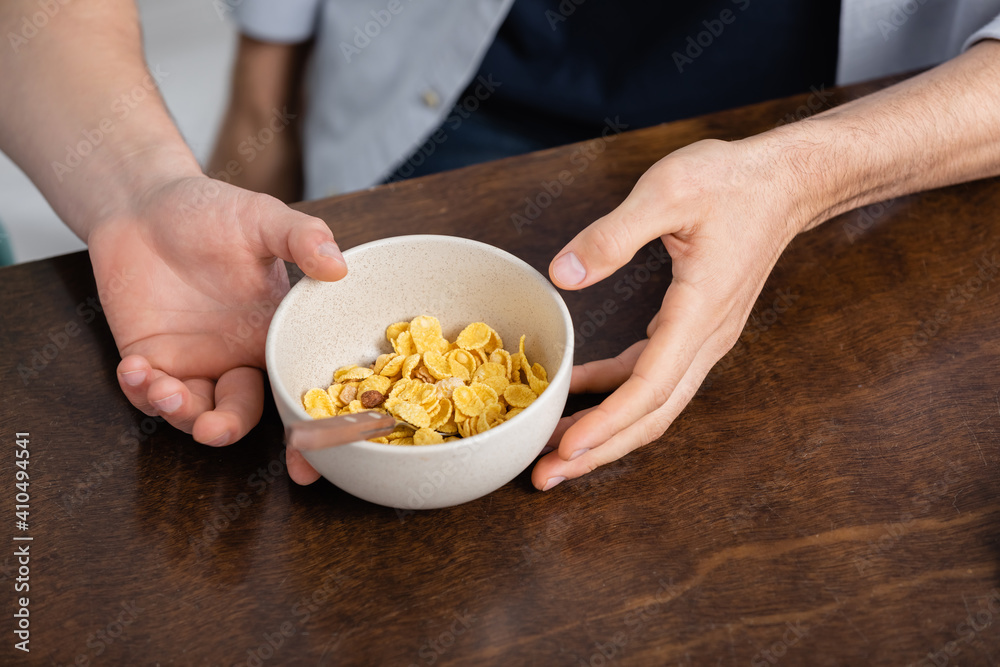 cropped view of homosexual men holding bowl with corn flakes