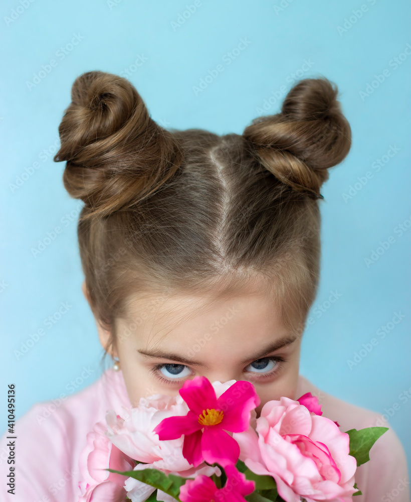 Naklejka premium Portrait. Girl 6-7 years old sniffing a bouquet of flowers and looking at the camera