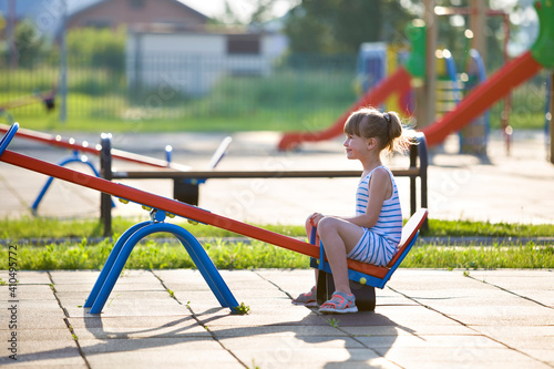 Valokuva Cute young child girl outdoors on see-saw swing on sunny summer day