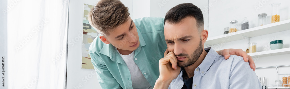 upset homosexual man looking at worried husband, banner - obrazy, fototapety, plakaty 