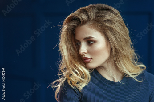 Fotografija close-up portrait of a blonde girl on a blue background in a blue dress