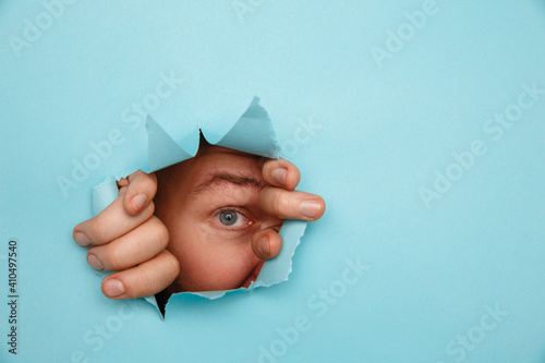 Eye looking through hole in paper.