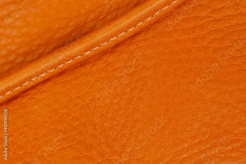 Texture of leather handbag with stitching, orange color, selecive focus, background, copy space