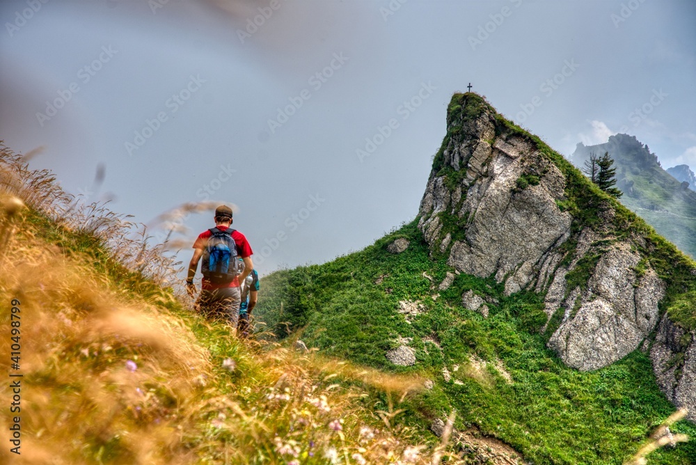 Men hikes in the mountain to mountain top cross in the swiss nature and mountain region of Speer, Federispitz, Chuemettler, Grappehorn