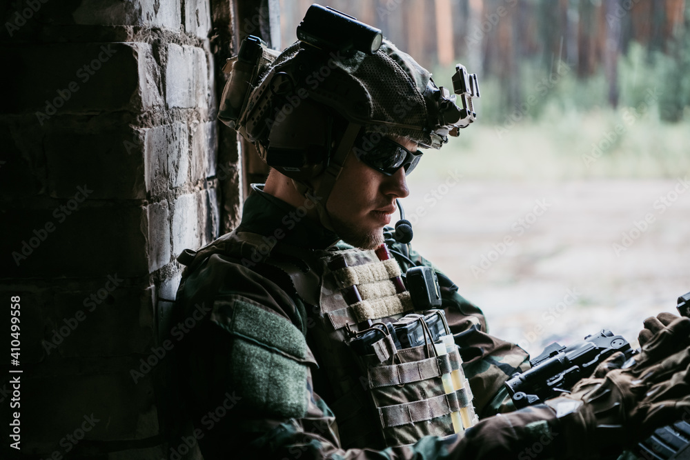 A thoughtful soldier, resting from a military operation while it is raining outside.